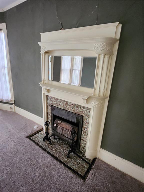 room details with a fireplace, carpet flooring, and baseboards