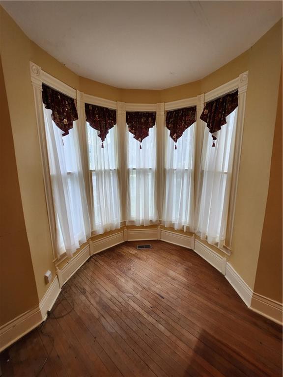 unfurnished dining area featuring visible vents, baseboards, and dark wood-style floors