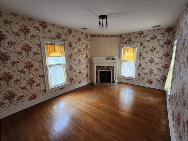 unfurnished living room with a high end fireplace, visible vents, hardwood / wood-style flooring, and baseboards