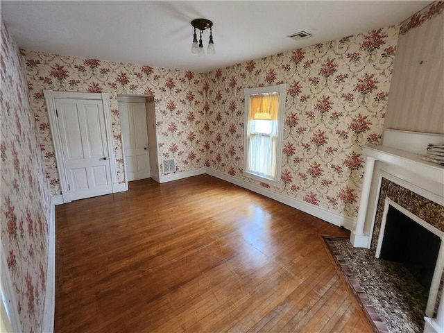 unfurnished living room with light wood finished floors, baseboards, visible vents, and a fireplace