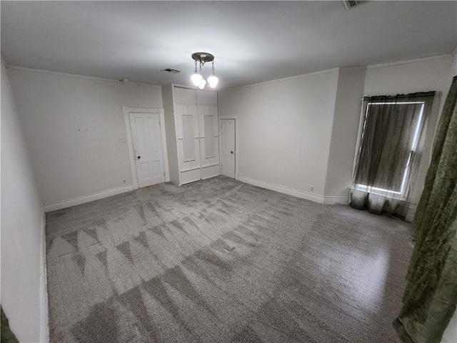 unfurnished room featuring crown molding, carpet flooring, baseboards, and visible vents