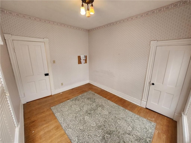 spare room with baseboards, wood finished floors, and wallpapered walls
