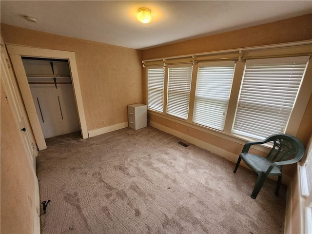 unfurnished bedroom featuring a closet, light colored carpet, baseboards, and visible vents