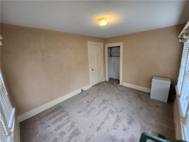unfurnished bedroom with carpet floors, baseboards, and a closet