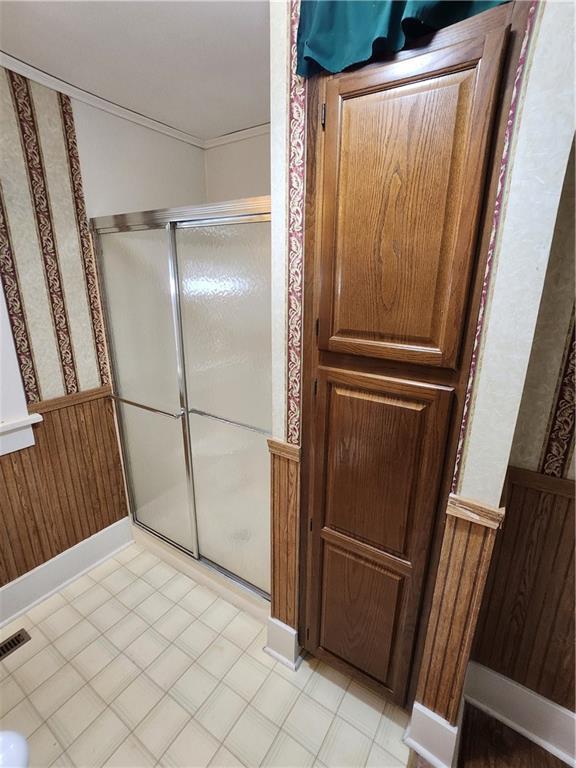 full bath featuring a shower stall, wallpapered walls, wainscoting, and visible vents