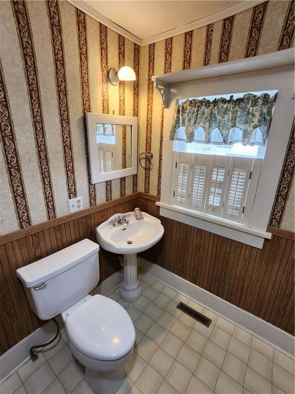 bathroom featuring visible vents, toilet, wainscoting, and wallpapered walls