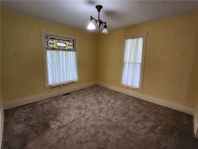 carpeted spare room featuring baseboards, visible vents, and a wealth of natural light