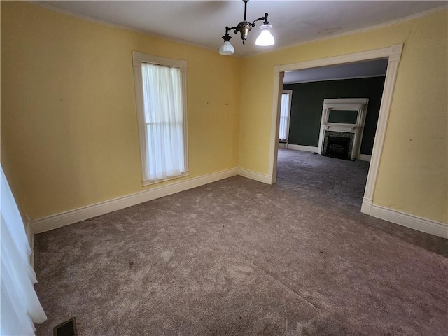 spare room with a chandelier, dark carpet, ornamental molding, and visible vents
