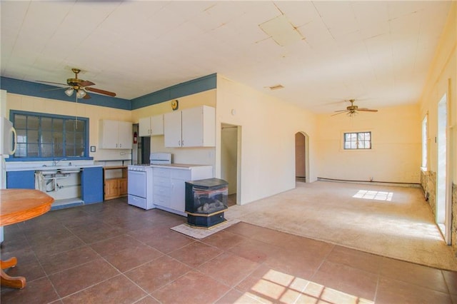 25388 Chieftain Rd, Lawrence, KS 66044 - kitchen with white gas stove, arched walkways, a ceiling fan, and a wood stove