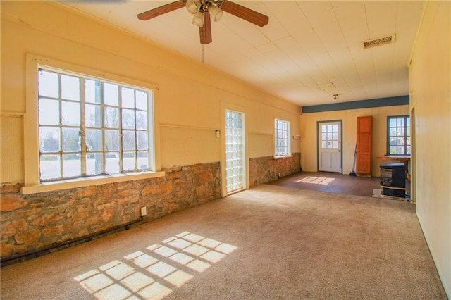 25388 Chieftain Rd, Lawrence, KS 66044 - carpeted empty room featuring a wood stove, a ceiling fan, and visible vents