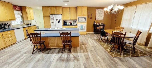 1463 Missouri Rd, Iola, KS 66749 - kitchen featuring white appliances, light wood-style floors, a chandelier, a kitchen island, and dark countertops