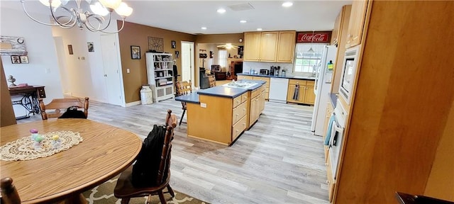 1463 Missouri Rd, Iola, KS 66749 - kitchen featuring white appliances, light wood-type flooring, a chandelier, a center island, and dark countertops