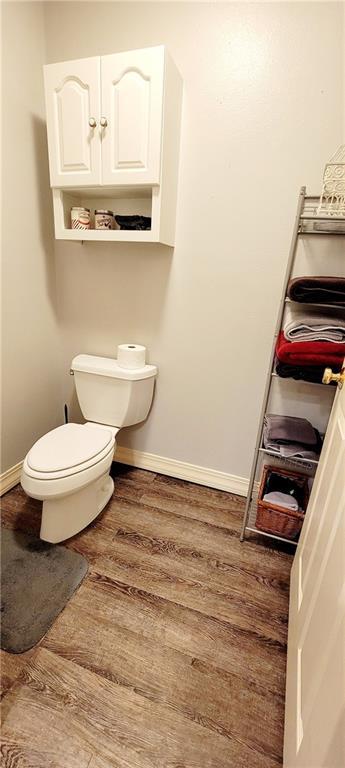 1463 Missouri Rd, Iola, KS 66749 - bathroom featuring wood finished floors, baseboards, and toilet