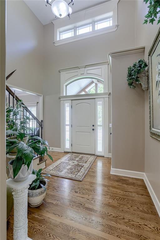 4102 NW 76th Ter, Kansas City, MO 64151 - foyer featuring a towering ceiling, wood finished floors, a chandelier, baseboards, and stairs