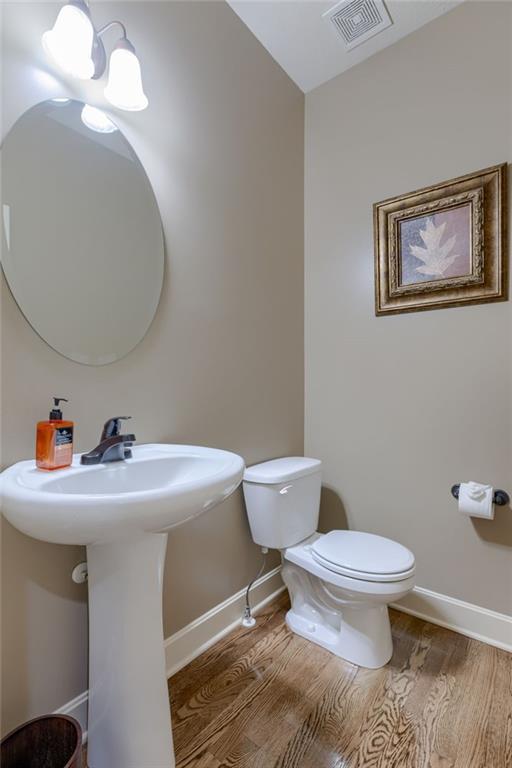 4102 NW 76th Ter, Kansas City, MO 64151 - half bath featuring toilet, baseboards, wood finished floors, and a sink