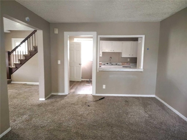 10816 E 27th St, Independence, MO 64052 - unfurnished living room featuring stairs, a sink, a textured ceiling, carpet, and baseboards