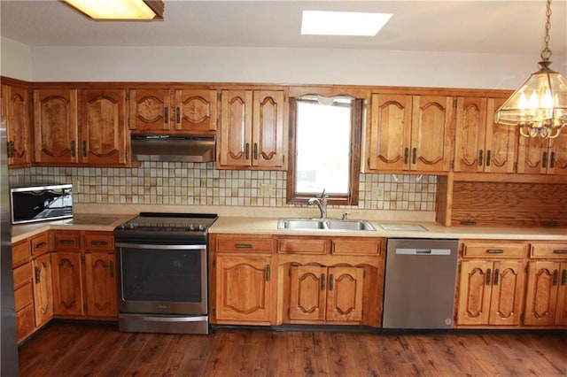1410 Grandview Dr, Warrensburg, MO 64093 - kitchen with under cabinet range hood, appliances with stainless steel finishes, a sink, light countertops, and brown cabinetry