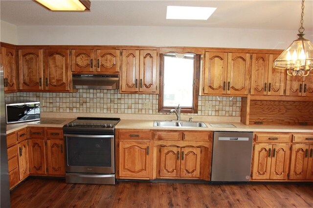 1410 Grandview Dr, Warrensburg, MO 64093 - kitchen with under cabinet range hood, appliances with stainless steel finishes, a sink, light countertops, and brown cabinetry