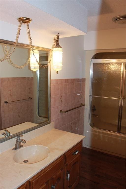 1410 Grandview Dr, Warrensburg, MO 64093 - full bath with tile walls, enclosed tub / shower combo, vanity, wood finished floors, and wainscoting