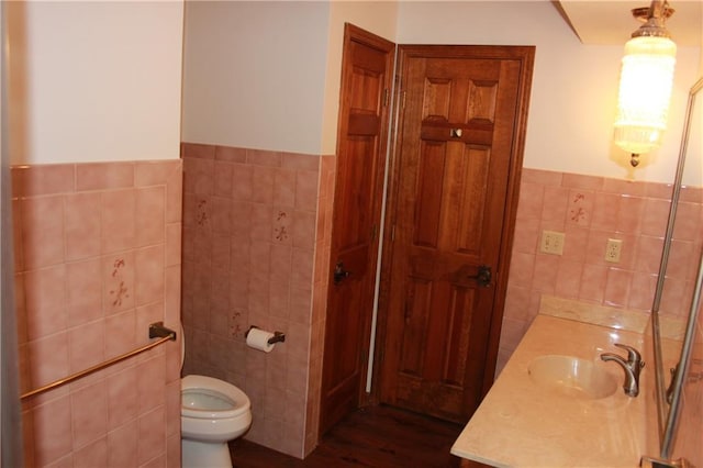 1410 Grandview Dr, Warrensburg, MO 64093 - bathroom featuring tile walls, toilet, wood finished floors, wainscoting, and vanity