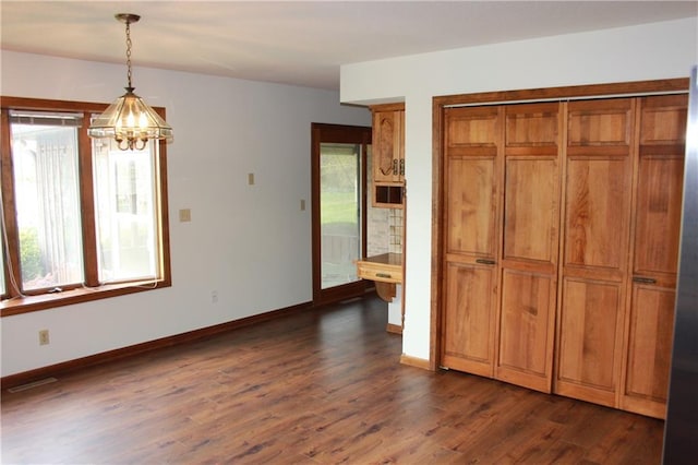 1410 Grandview Dr, Warrensburg, MO 64093 - unfurnished dining area with a chandelier, healthy amount of natural light, dark wood-style flooring, and baseboards