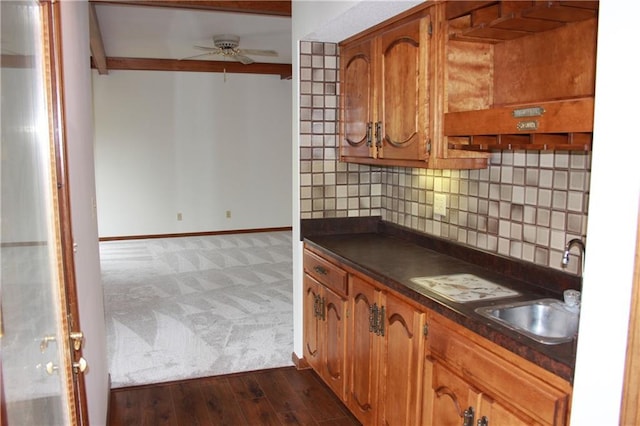 1410 Grandview Dr, Warrensburg, MO 64093 - kitchen featuring dark countertops, dark carpet, a sink, backsplash, and brown cabinetry