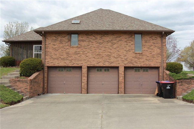 1410 Grandview Dr, Warrensburg, MO 64093 - view of side of home featuring an attached garage, driveway, roof with shingles, and brick siding