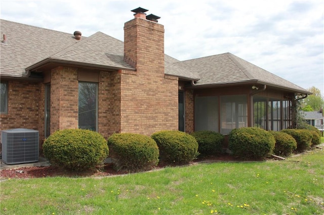 1410 Grandview Dr, Warrensburg, MO 64093 - view of side of home featuring a chimney, central AC, brick siding, a sunroom, and a lawn