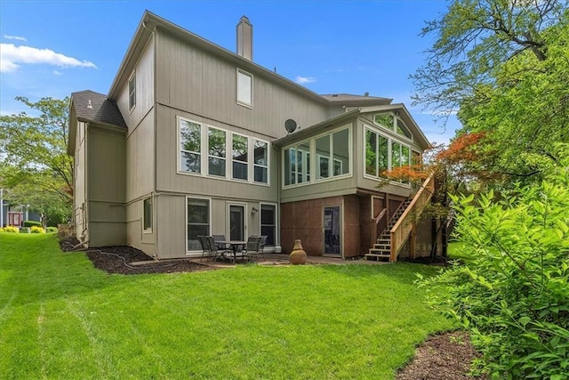 rear view of house with stairs, a yard, a chimney, a patio, and roof with shingles