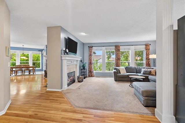 living room featuring light wood finished floors, baseboards, and a tile fireplace