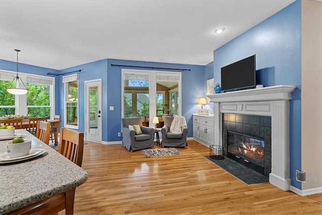 living area featuring light wood-style floors, baseboards, a fireplace, and a textured ceiling