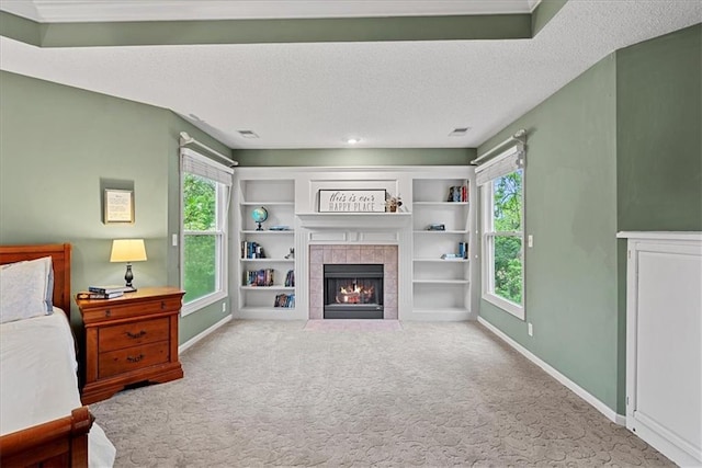 living area with carpet flooring, baseboards, healthy amount of natural light, a tile fireplace, and a textured ceiling