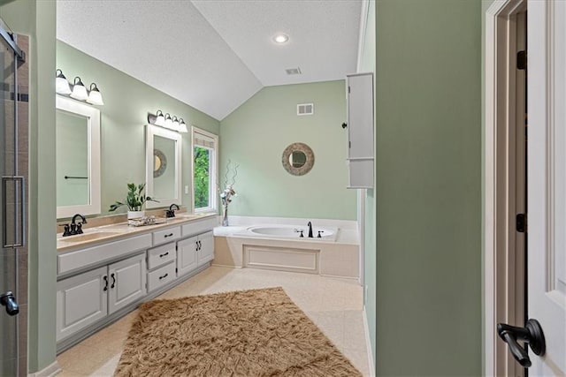 bathroom featuring vaulted ceiling, a garden tub, a textured ceiling, a shower stall, and double vanity