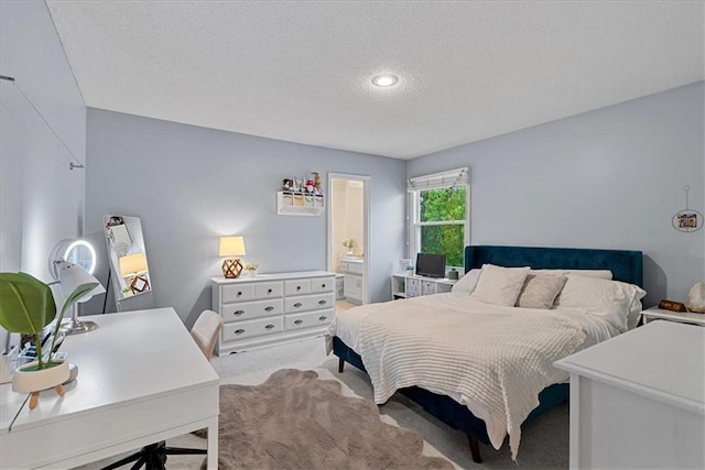 bedroom featuring light carpet, a textured ceiling, an office area, and connected bathroom