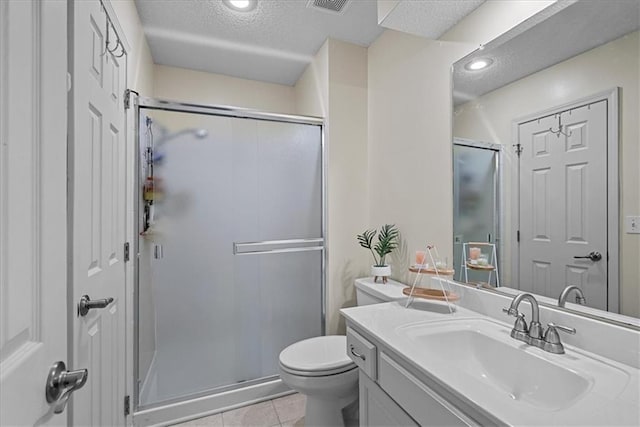 full bathroom featuring a shower stall, a textured ceiling, vanity, tile patterned flooring, and toilet