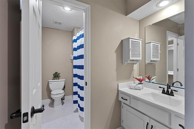 bathroom with toilet, vanity, a textured ceiling, baseboards, and tile patterned floors