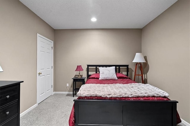 bedroom with light carpet, a textured ceiling, and baseboards