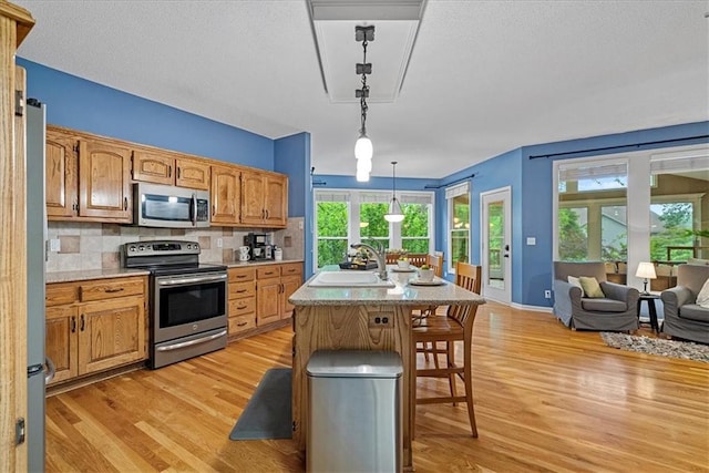 14124 Flint St, Overland Park, KS 66221 - kitchen with stainless steel appliances, a sink, light wood-style flooring, light countertops, and a textured ceiling