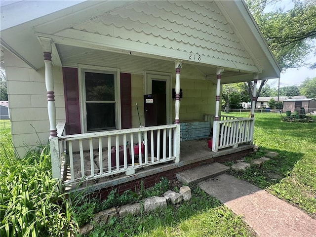 218 S Kent St, Excelsior Springs, MO 64024 - property entrance featuring a porch, a lawn, and a tile roof