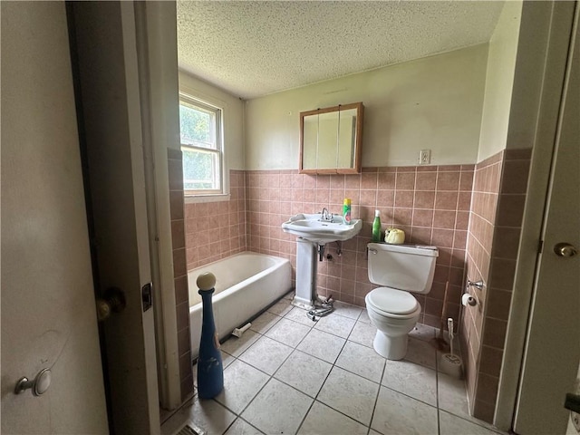 218 S Kent St, Excelsior Springs, MO 64024 - full bathroom featuring toilet, a bathtub, a textured ceiling, a wainscoted wall, and tile patterned floors
