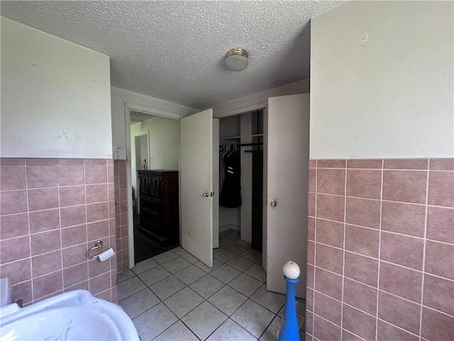 218 S Kent St, Excelsior Springs, MO 64024 - full bath with tile walls, tile patterned flooring, a wainscoted wall, a textured ceiling, and a tub