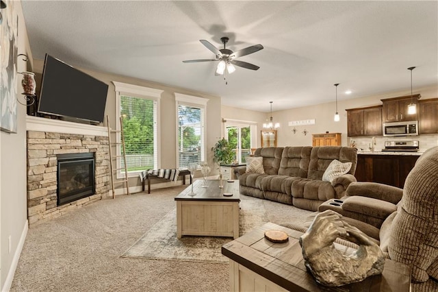 19625 E 18th Ter, Independence, MO 64057 - living room with ceiling fan, light carpet, a stone fireplace, baseboards, and a chandelier