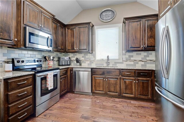 kitchen featuring lofted ceiling, stainless steel appliances, a sink, and dark brown cabinets
