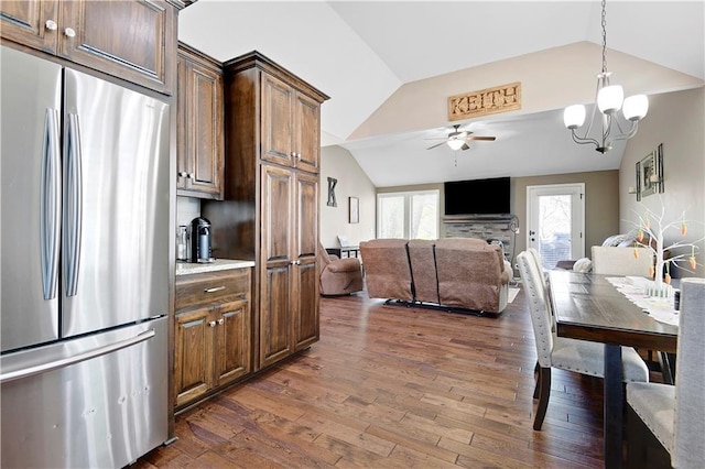 kitchen with dark wood-style floors, open floor plan, vaulted ceiling, freestanding refrigerator, and ceiling fan with notable chandelier