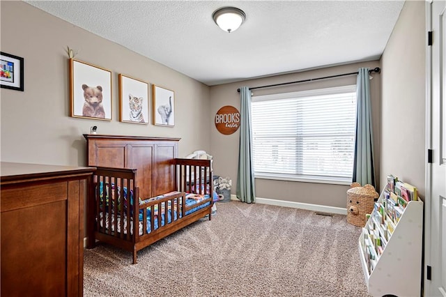 carpeted bedroom with baseboards, a crib, and a textured ceiling