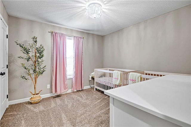 carpeted bedroom featuring baseboards, visible vents, a textured ceiling, and a nursery area