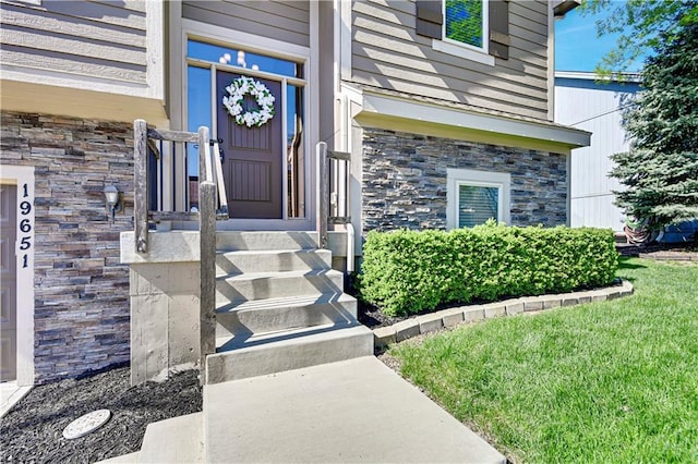 entrance to property with stone siding and a yard