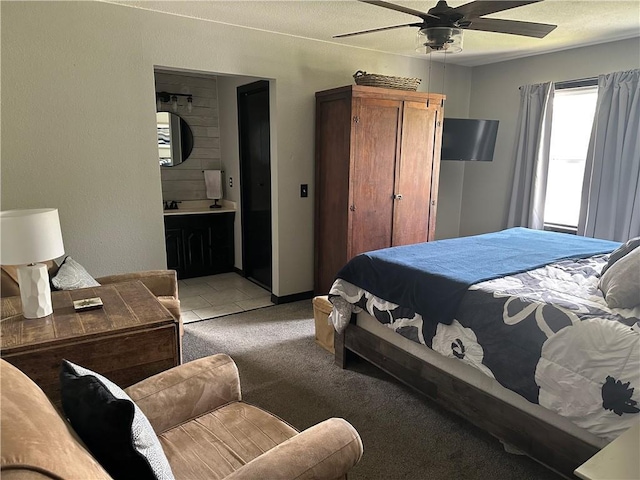 bedroom with ensuite bathroom, light colored carpet, and a ceiling fan