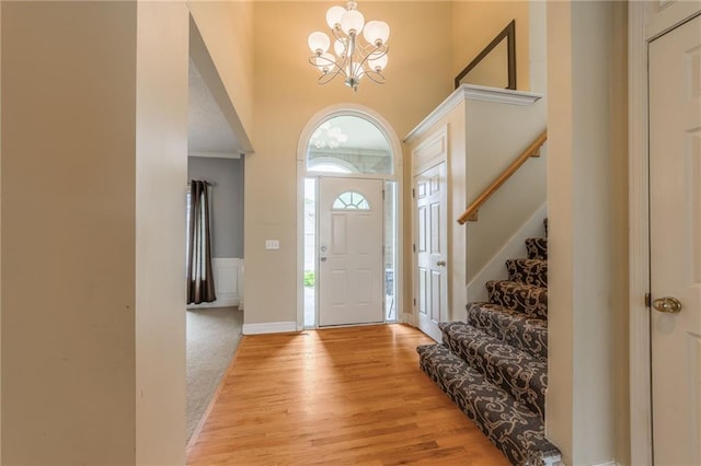 7428 N Smalley Ave, Kansas City, MO 64158 - entryway with a chandelier, stairs, a towering ceiling, light wood-style flooring, and baseboards