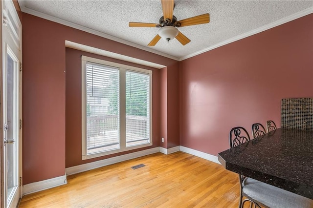 7428 N Smalley Ave, Kansas City, MO 64158 - dining area featuring light wood-style flooring, a textured ceiling, baseboards, a ceiling fan, and crown molding
